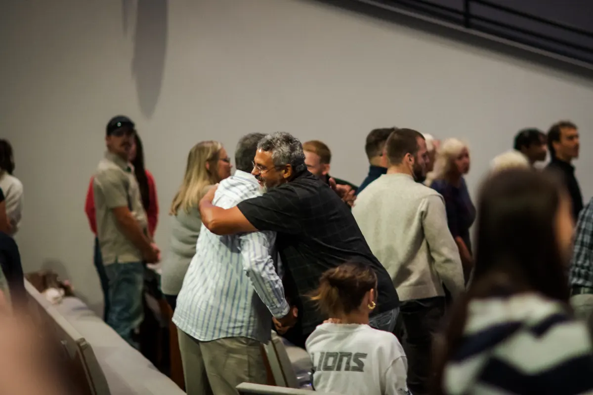 Church members hugging and greeting each other in the aisle